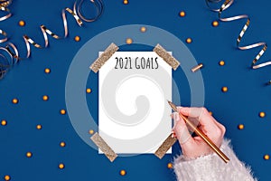 Woman writes New Year Resolutions. Flat lay image in gold and classic blue colors with isolated white card