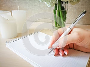 A woman writes in a notebook with a beautiful pen.