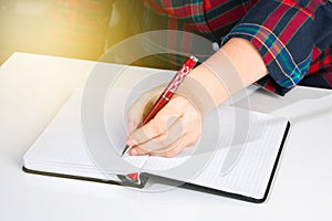 Woman writes in a notebook and holds pen with her left hand. The girl works in the office. Left-handers Day August 13th