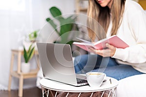 Woman writes in notebook with laptop