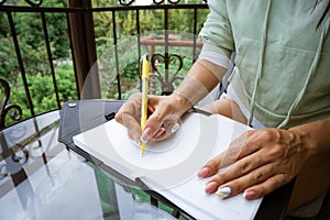 woman writes in a notebook at a table on the terrace