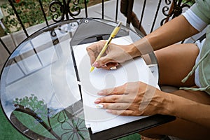 woman writes in a notebook at a table on the terrace