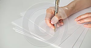 A woman writes with a pen on a white blank sheet of paper