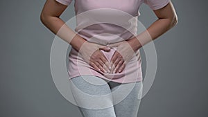 Woman writhing from pain in lower abdomen, menstrual pain, risk of miscarriage