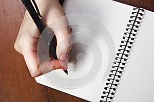 Woman writing with black pen on notebook