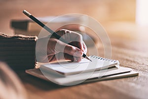 A woman writing on blank notebook on wooden table