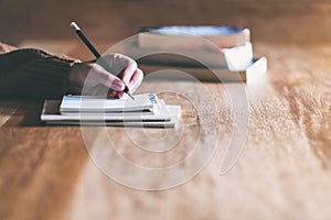 A woman writing on blank notebook on wooden table