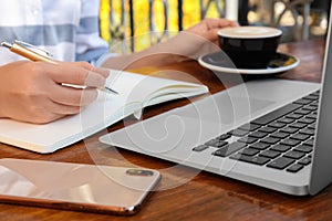 Woman writing blog content in notebook at table