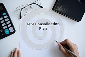 Woman writing debt consolidation plan in paper on desk. Copy space, top view