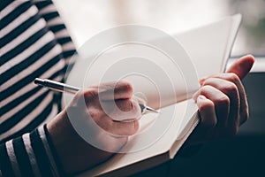 Woman writing diary by the window photo