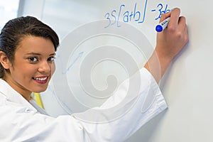 Woman writing equations on white board