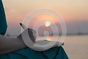 Woman writing in her diary at sunset photo