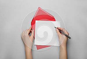 Woman writing letter on grey background, top view