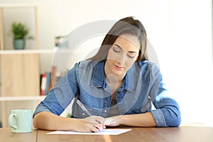 Woman writing a letter on a table at home