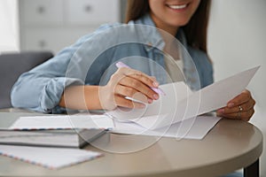 Woman writing letter at table indoors, closeup