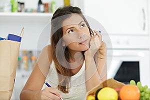 woman writing list in kitchen