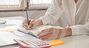 The woman is writing a message in the book on table.