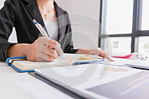 The woman is writing a message in the book on table.