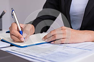 The woman is writing a message in the book on table.