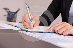 The woman is writing a message in the book on table.