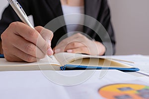 The woman is writing a message in the book on table.