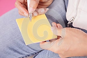 Woman writing message on yellow note paper