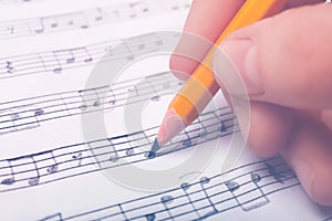Woman writing music notes on sheet with pencil