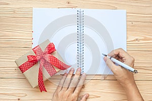 Woman writing with notebook and Christmas decoration on wooden table, Top view and copy space. Goals, Resolution, Solution, Strate