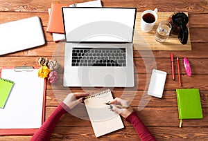 Woman writing in notebook with pen at desk