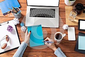 Woman writing in notebook with pen at desk