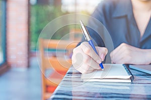 Woman is writing on a notebook with a pen in the office