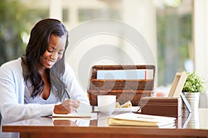 Woman Writing In Notebook Sitting At Desk