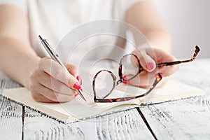 Woman writing in notepad placed on bright desktop. Education con