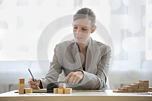 Woman writing on notepad beside wooden blocks