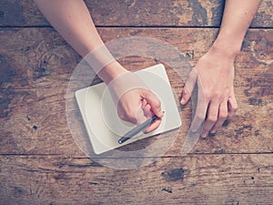 Woman writing in notepad at wooden table