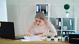 Woman writing on paper and crumpling it