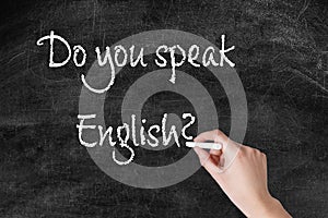 Woman writing question DO YOU SPEAK ENGLISH on blackboard