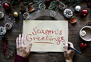 Woman writing a Season`s Greetings card