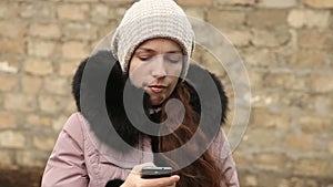 Woman writing sms in winter clothes on smartphone