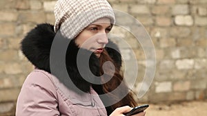 Woman writing sms in winter clothes on smartphone