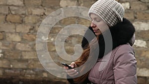 Woman writing sms in winter clothes on smartphone