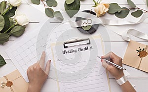 Woman writing wedding items in checklist for planning budget