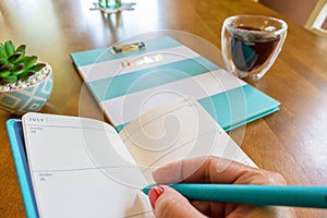 Woman writing in weekly planner with turquoise colored pen