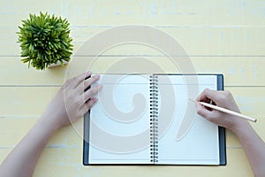 The woman wrote the book with a clay book in a yellow background. The top view