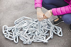 Woman's arms trying to raise a heavy metallic chain