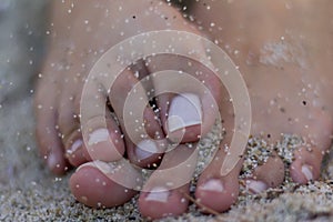 Woman's feet on the white sand, with sand