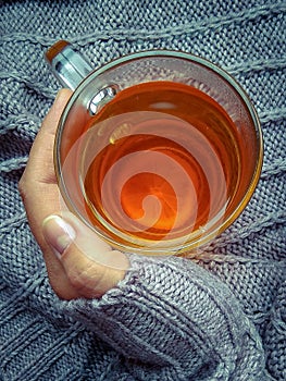 A woman& x27;s hand holds a Cup of hot tea with lemon