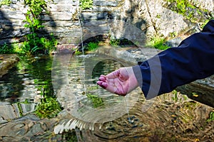 A woman& x27;s hand taking fresh water from an old fountain in the village of Patones de Arriba. photo