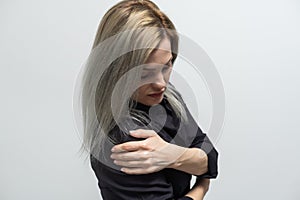 woman& x27;s hand in white t-shirt touch her upper arm , arm pain and muscle injury concept.