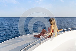 Woman on a Yacht in the Sea. Luxury vacation on a boat near the islands in the summer. Beautiful sexy girl relaxing and